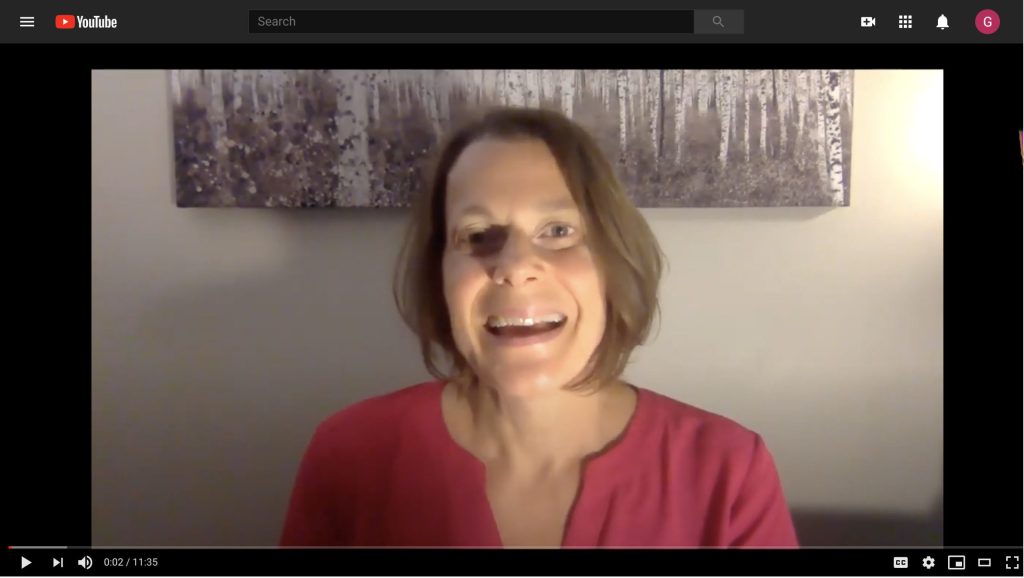Video still of a smiling white woman wearing a pink top.